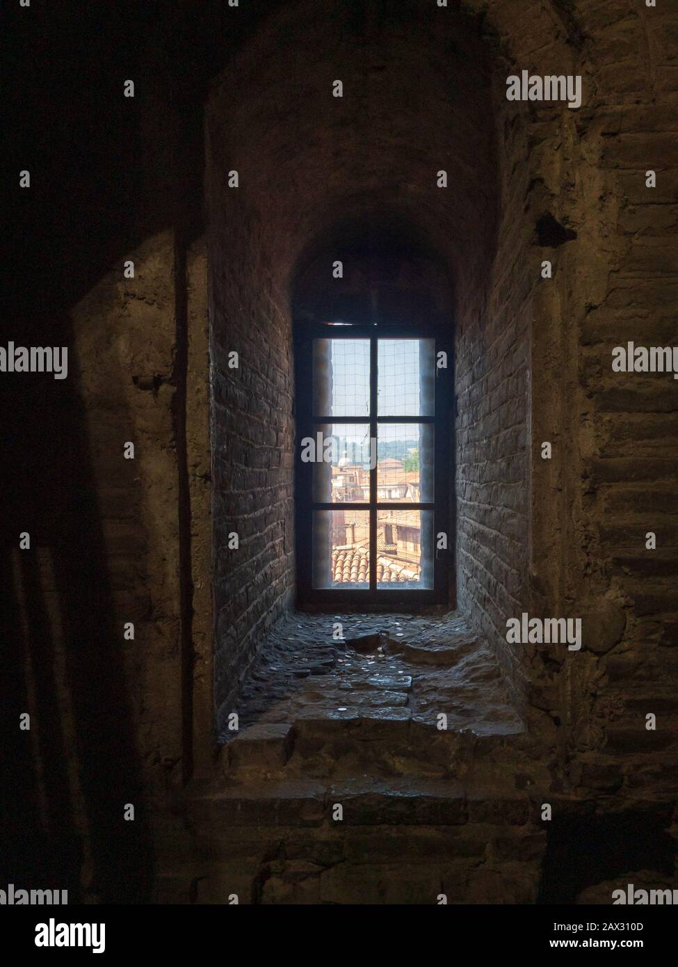Guardando attraverso una finestra dall'interno della Torre Asinelli con monete davanti ad essa a Bologna, Italia Foto Stock