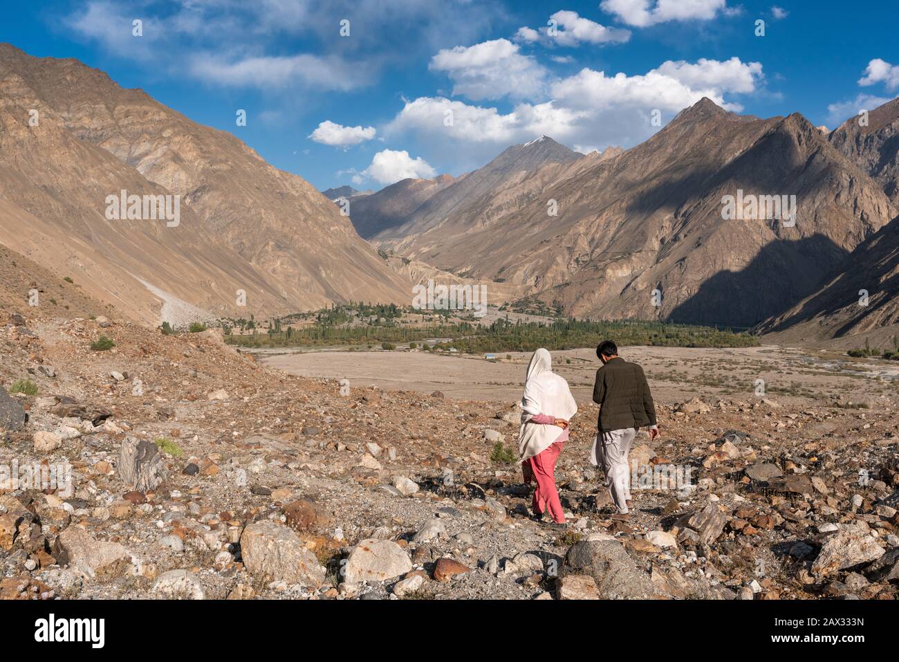 Uomo e donna locali che camminano insieme nella valle montuosa di Yasin, Gilgit Baltistan, Pakistan settentrionale Foto Stock