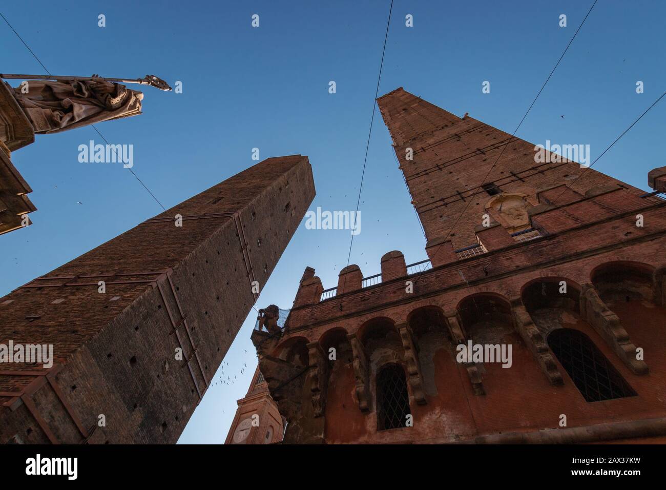 Vista ad angolo basso di due torri (due torri Asinelli e Garisenda) e la statua di San Petronio a Bologna, Italia Foto Stock