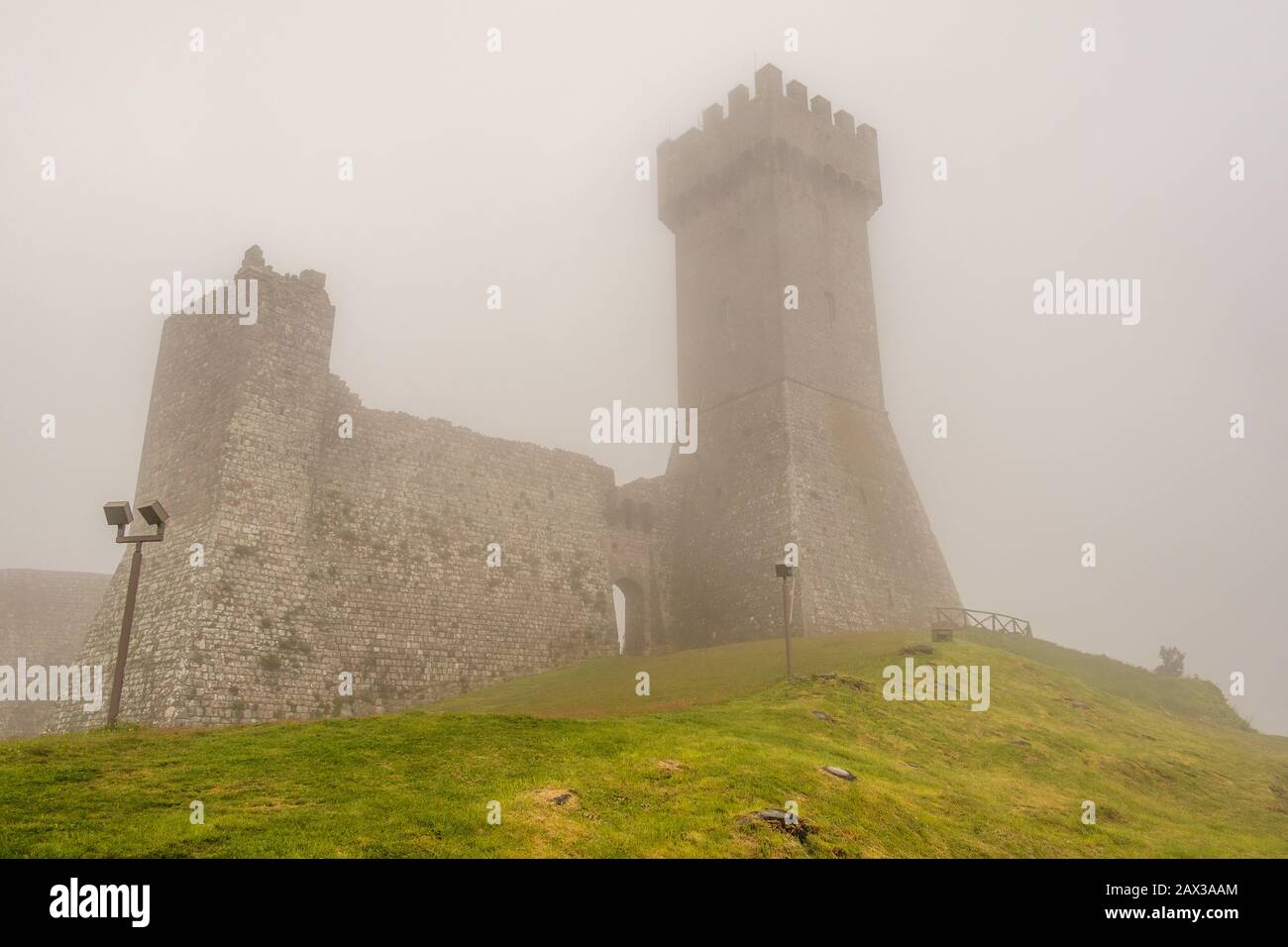 Castello di Radicofani in nebbia situato in posizione strategica sulla Via Francigena, con fortificazioni per fermare l'avanzata di Federico Barbaros Foto Stock