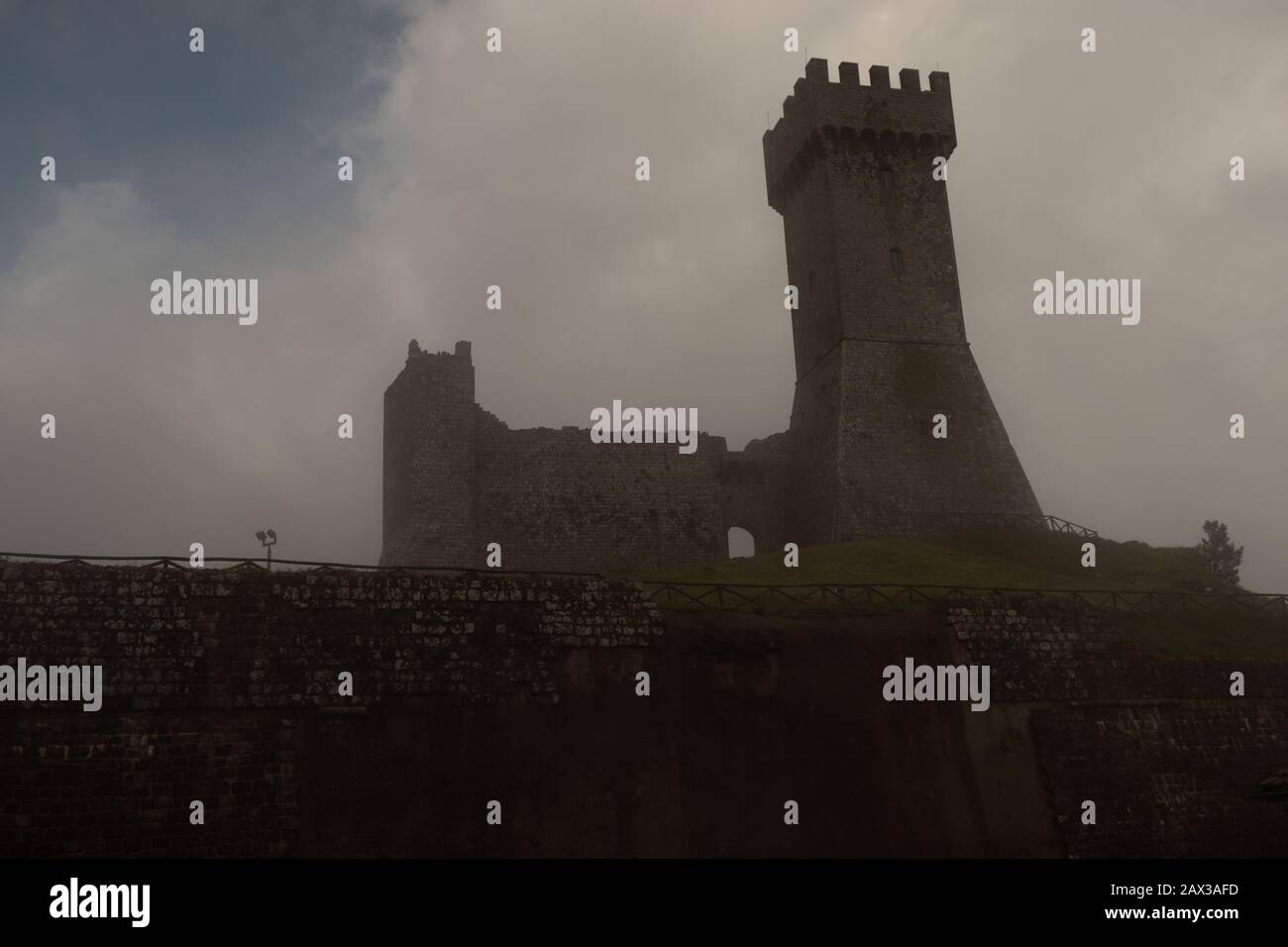 Castello di Radicofani in nebbia situato in posizione strategica sulla Via Francigena, con fortificazioni per fermare l'avanzata di Federico Barbaros Foto Stock