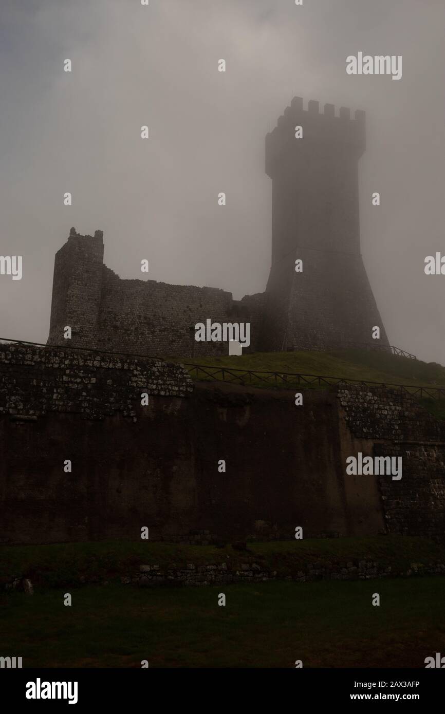 Castello di Radicofani in nebbia situato in posizione strategica sulla Via Francigena, con fortificazioni per fermare l'avanzata di Federico Barbaros Foto Stock