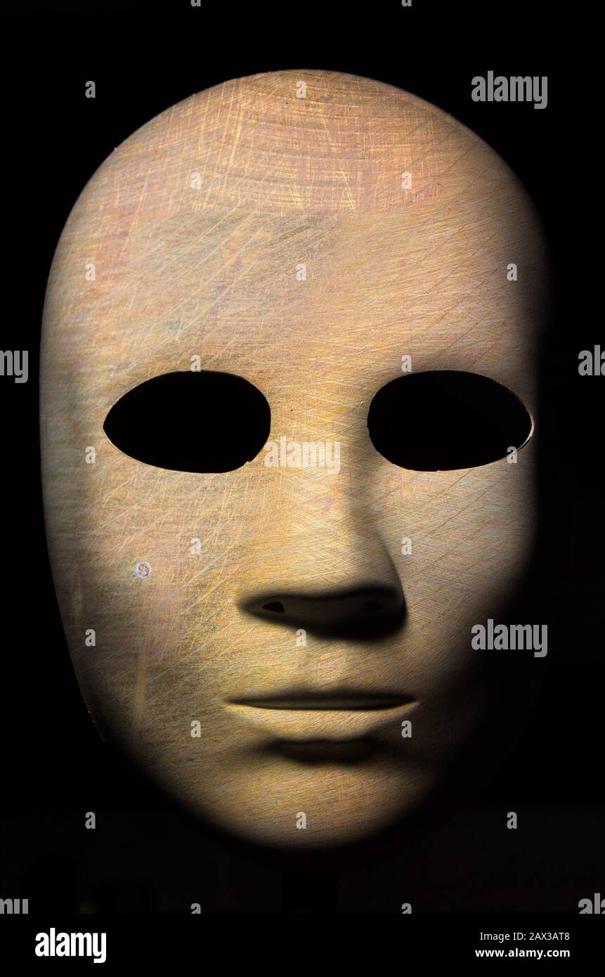 Maschera a trama con incrinato legno ruvida la superficie verniciata, espressione neutrale su sfondo scuro. Foto Stock