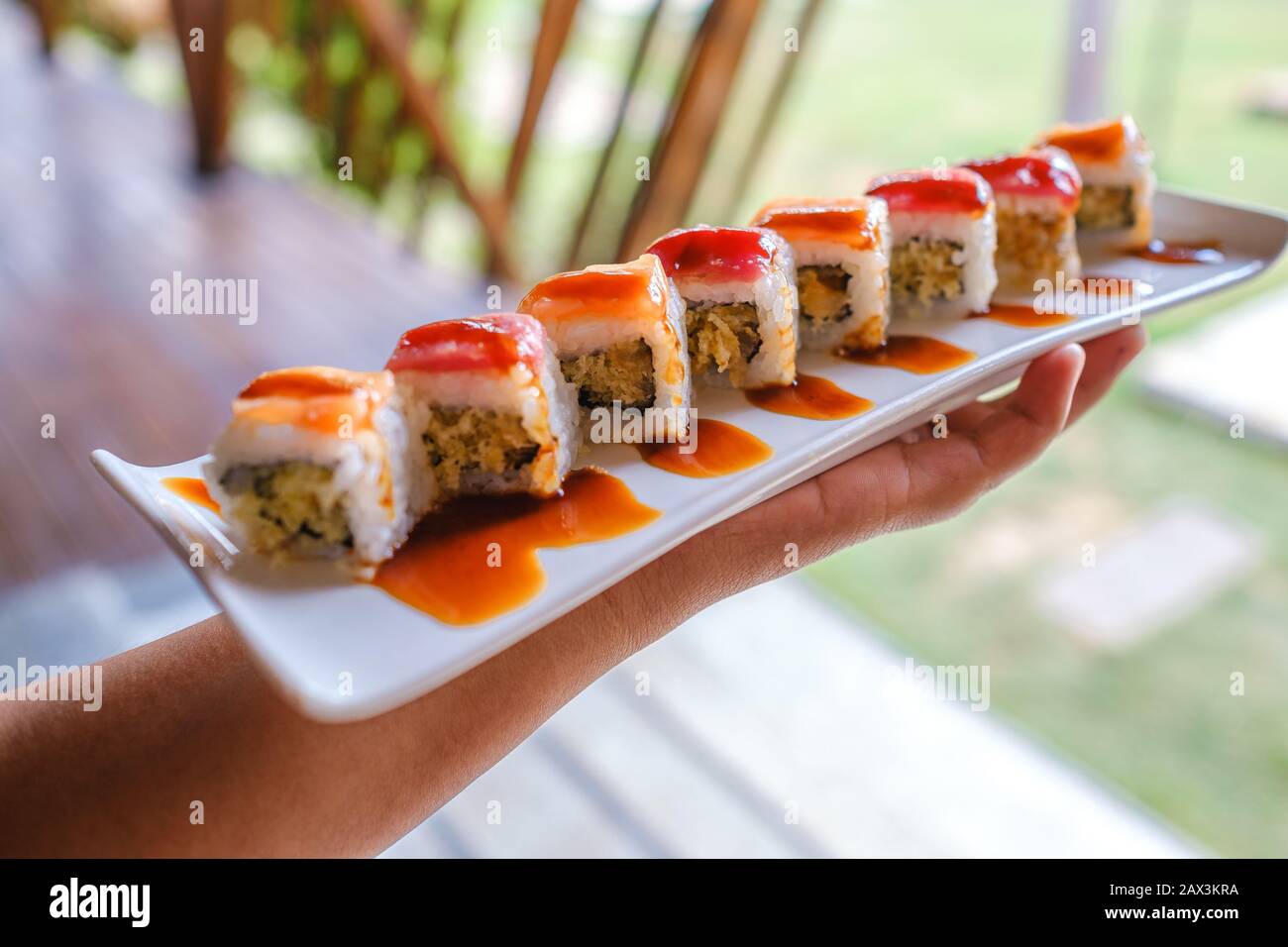 Primo piano di qualcuno che tiene un vassoio di diversi tipi di sushi Foto Stock