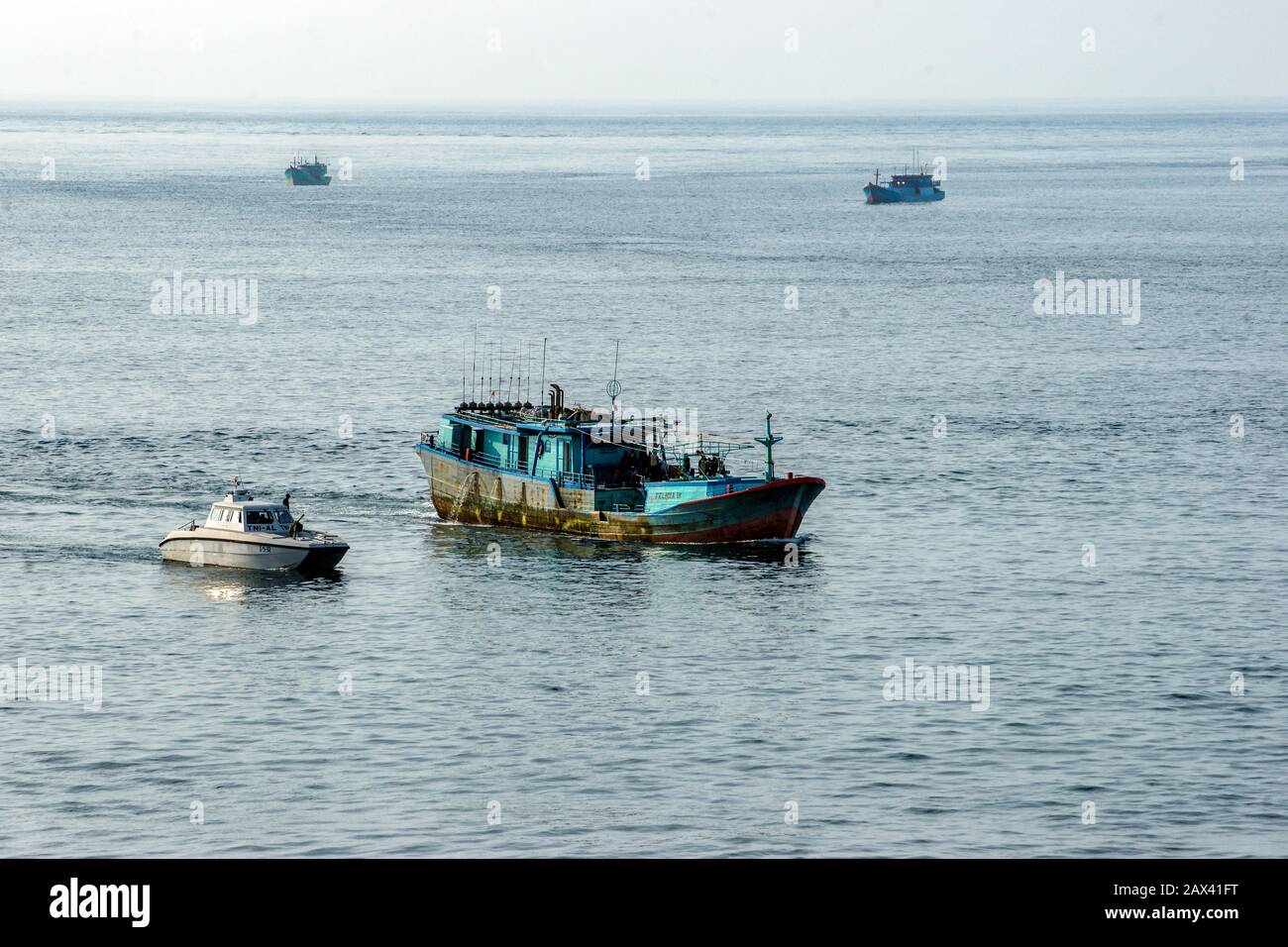 Bali, Indonesia. Barche da pesca di ritorno al mattino presto. Una barca della Guardia Costiera che arriva al lato di una barca. Foto Stock