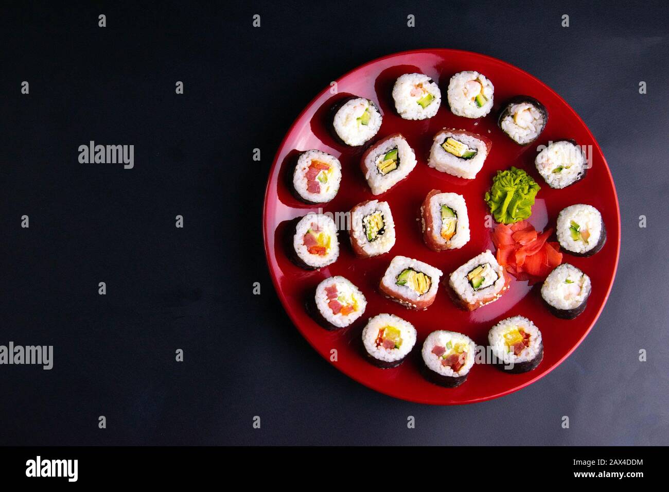 Rotoli di diversi tipi sono disposti su un piatto rosso con salsa di