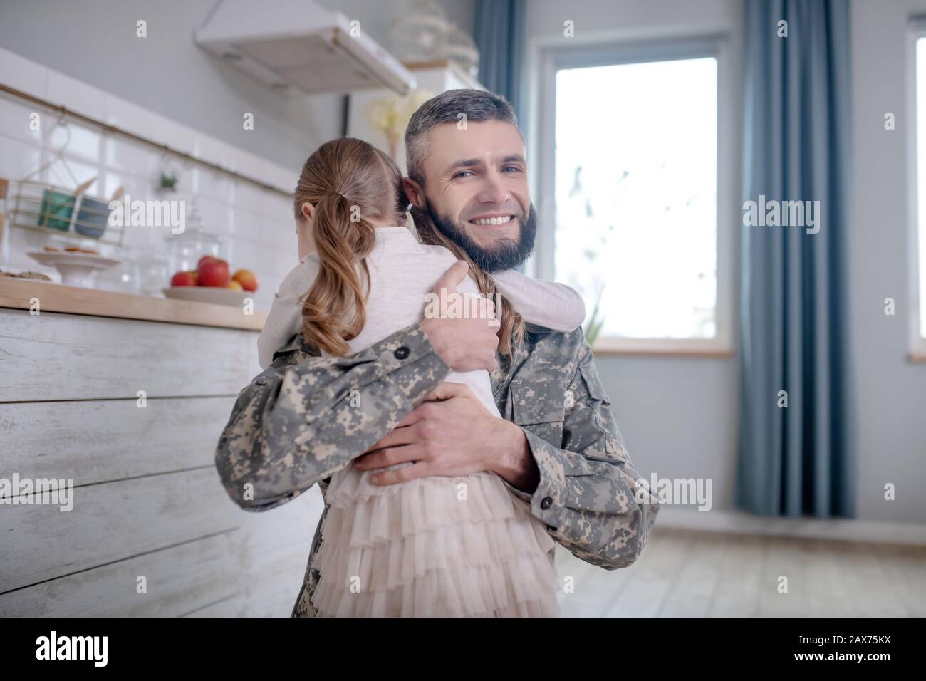 Il padre del serviceman che ritorna a casa abbracciando la figlia piccola. Foto Stock