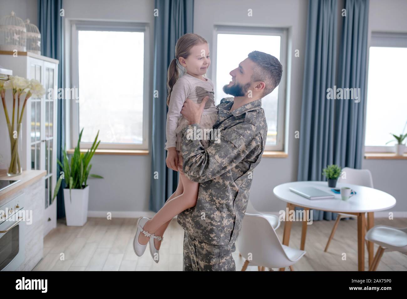 Giovane ufficiale che tiene una bambina tra le braccia. Foto Stock