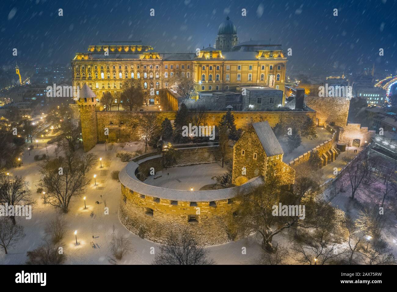 Budapest, Ungheria - Vista aerea del Castello di Buda illuminato Palazzo reale in una serata invernale innevata Foto Stock