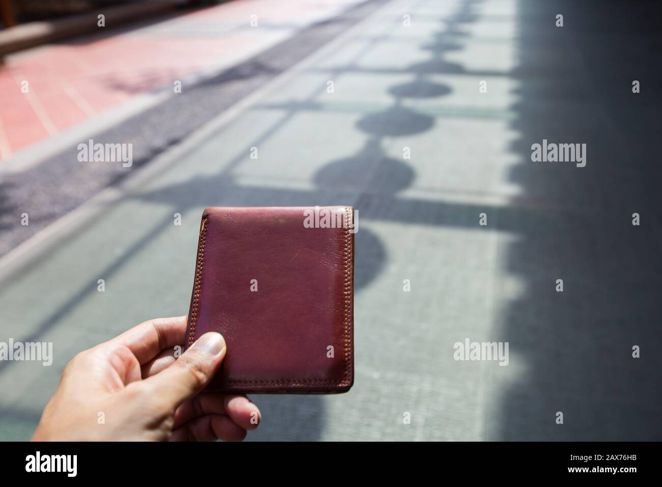 Prelevare un portafoglio lasciato sul pavimento nell'area pubblica. Foto Stock