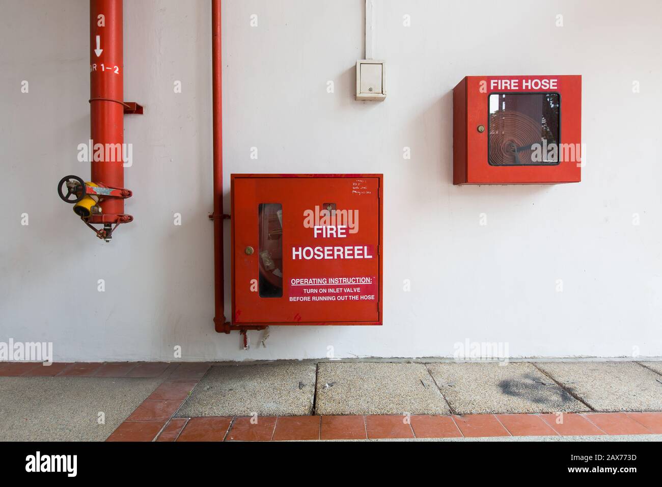 Minimalismo geometrico. Varie attrezzature antincendio montate a parete negli spazi pubblici. Utilizzare solo in situazioni di emergenza. Singapore. Foto Stock
