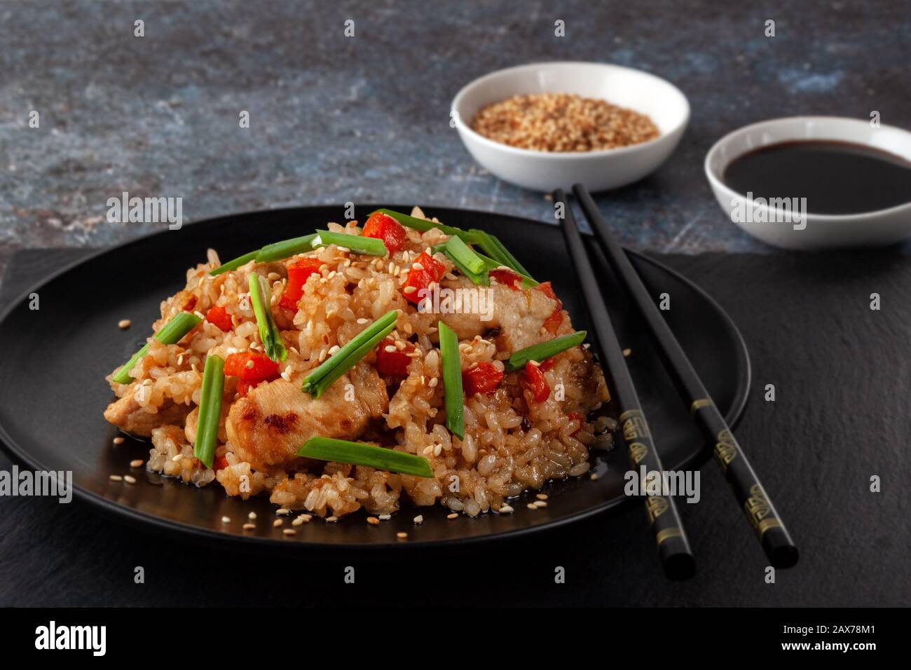 Tori chahan riso giapponese fritto con verdure e pollo in salsa di soia in una piastra nera su un tavolo da servizio Foto Stock