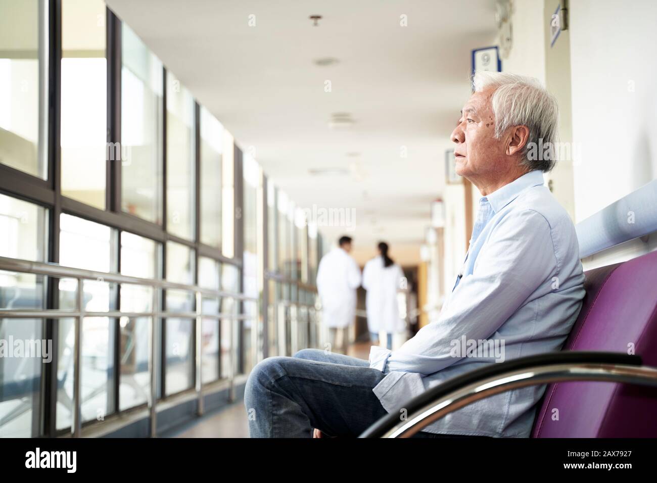 vecchio asiatico seduto nel corridoio dell'ospedale che guarda triste e depresso Foto Stock