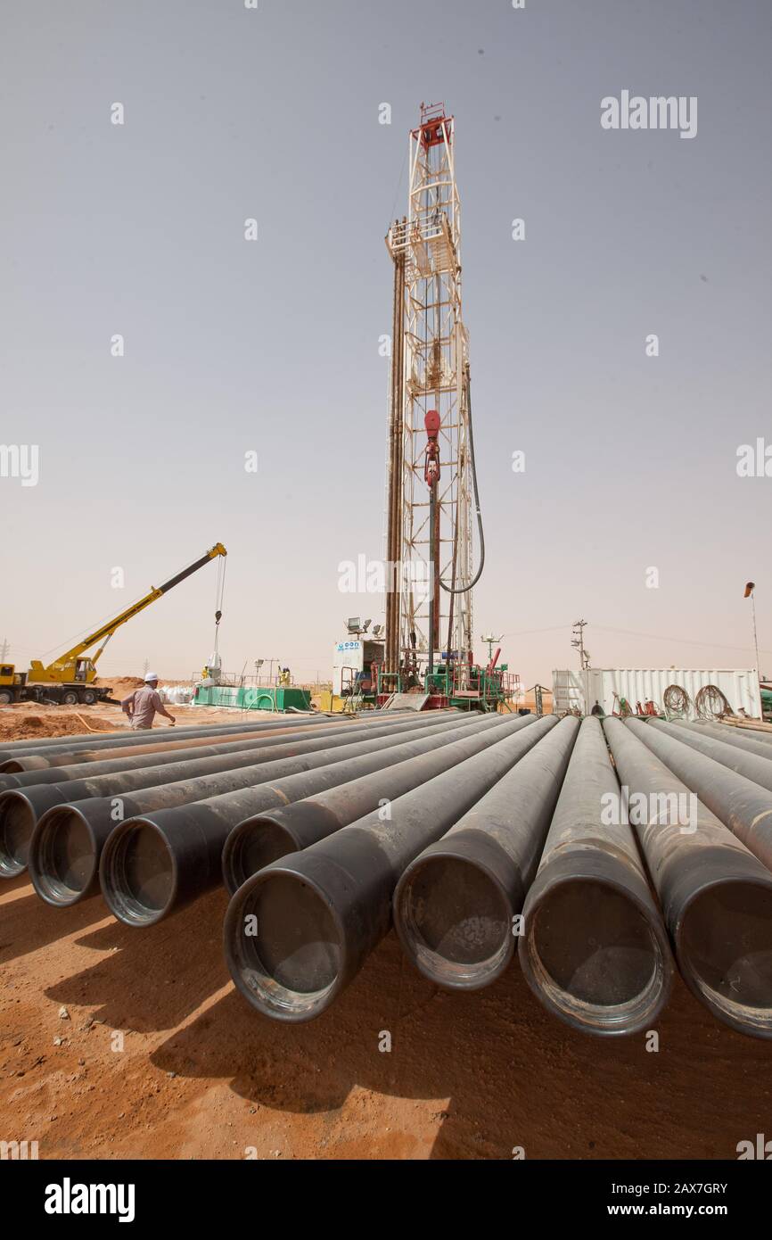 I tubi sono allineati a un carro di perforazione petrolifera nel deserto. Foto Stock