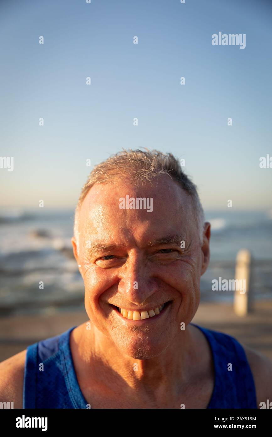 Jogger sorridente e guardando la macchina fotografica sul mare Foto Stock