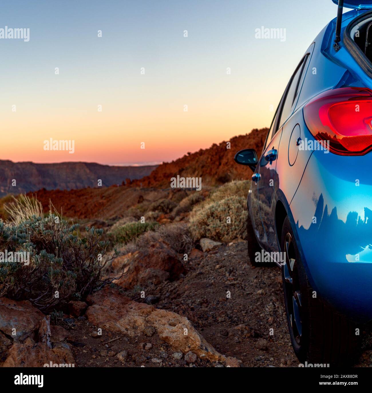 Auto da turismo in fuoristrada con paesaggio al tramonto. Vista ravvicinata dell'auto blu. Foto Stock