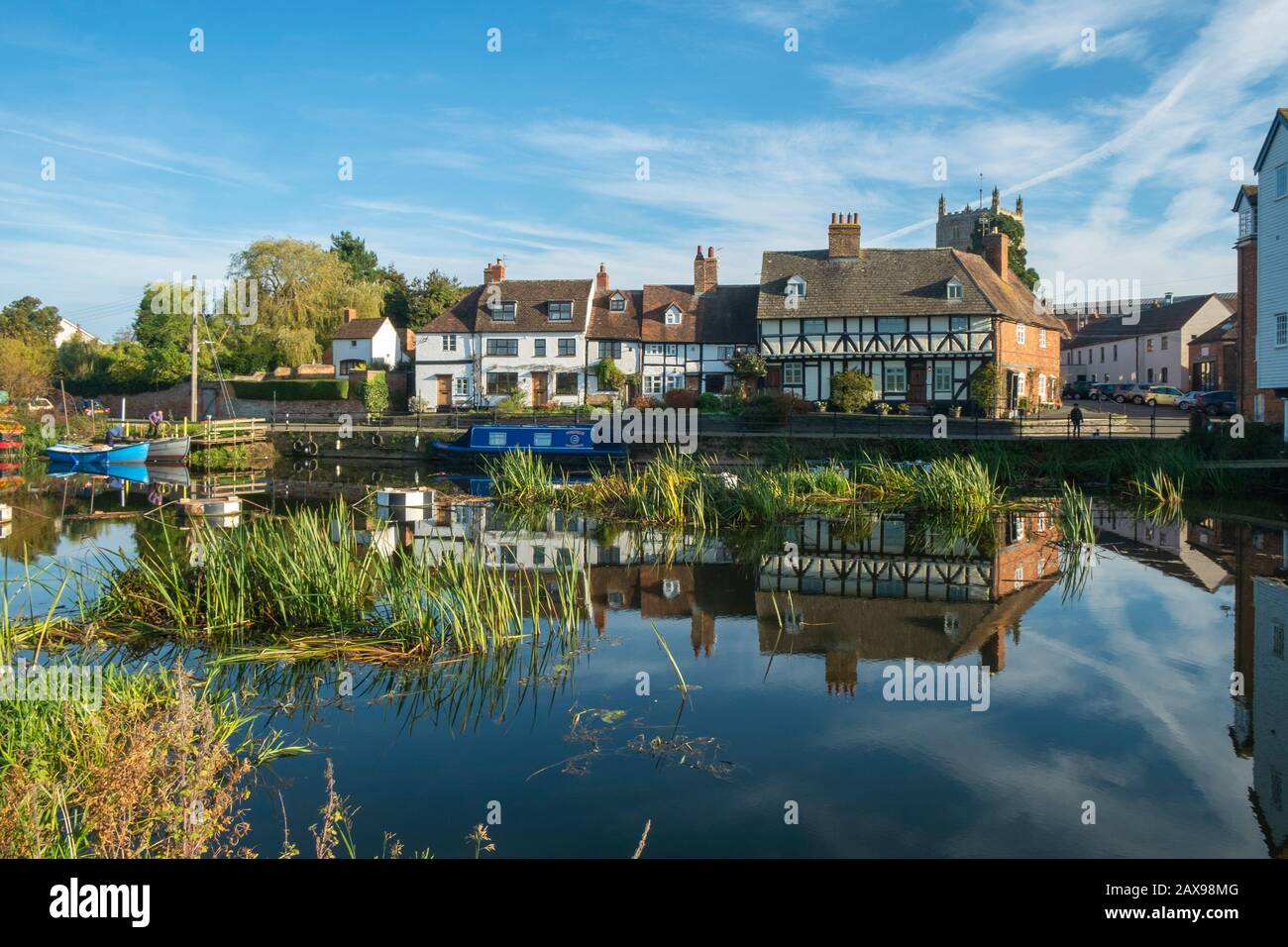 24 Ottobre 2018 - Tewkesbury, UK:due persone lavorano su una piccola barca ormeggiata vicino da un pittoresco gruppo di cottage che si riflettono nel tranquillo fiume Avon vicino Abbey Mill nella città di Tewkesbury, Gloucestershire, Severn vale, UK Foto Stock