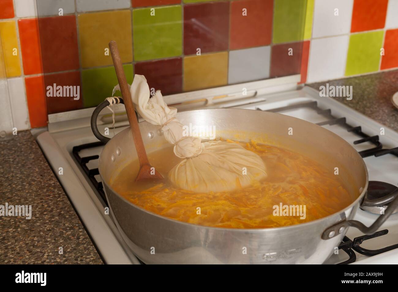 Bollendo giù le arance di Siviglia in un grande marmellata o marmellata che fa la vaschetta che simmering fuori dell'acqua eccedente con il sacchetto di muslin contenente la fonte dei semi di pectina pips Foto Stock