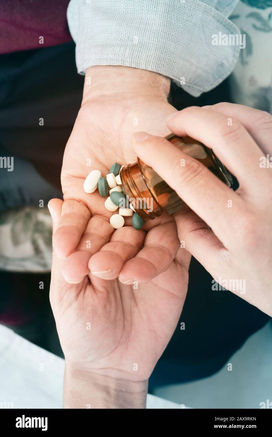 closeup di un medico caucasico uomo, in una mano bianca, dando alcune pillole ad un uomo caucasico anziano, nella sua casa o in una casa di cura Foto Stock