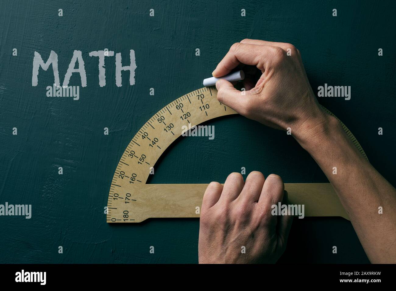 closeup di un uomo caucasico che usa un goniometro e il testo matematica, per la matematica, su una lavagna verde Foto Stock