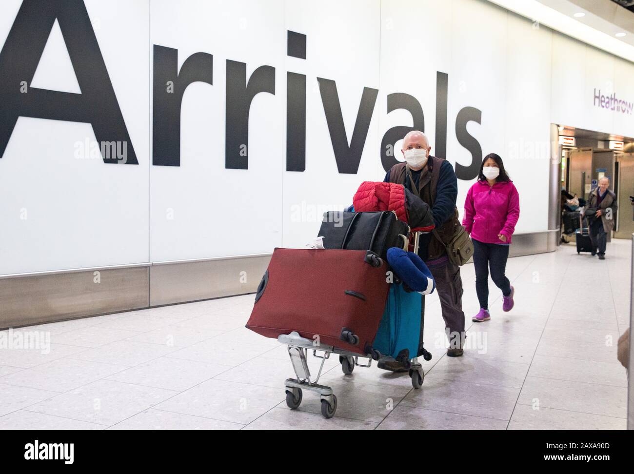 I passeggeri che indossano le maschere arrivano al Terminal 4 Heathrow. C'è un grande senso di preoccupazione per la salute pubblica con il tributo di morte per il Coronavirus che sale. Foto Stock