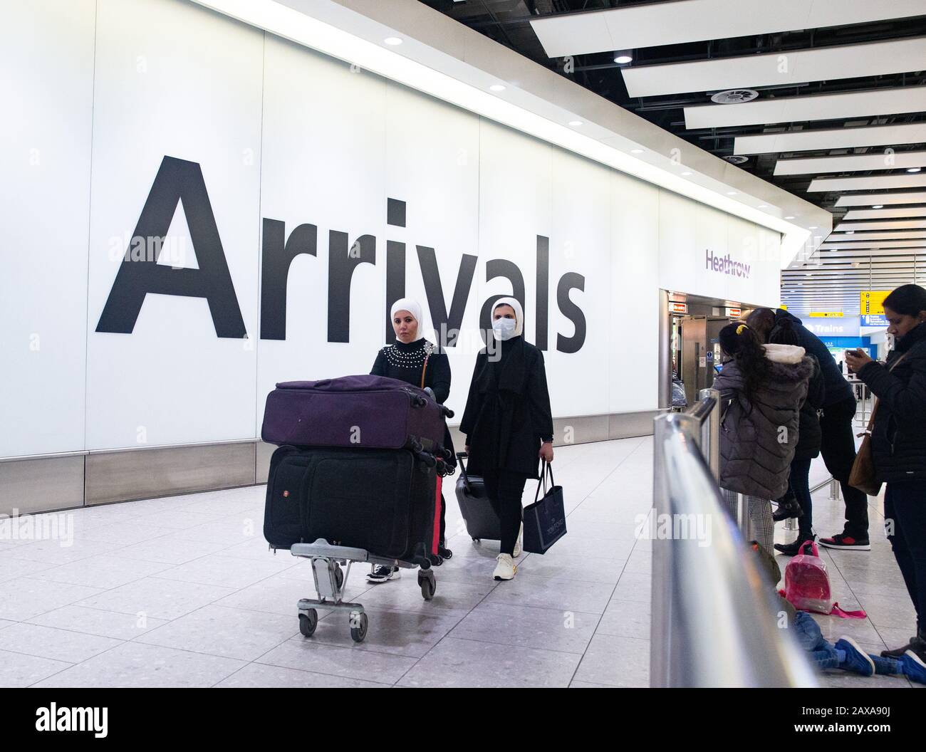 I passeggeri che indossano le maschere arrivano al Terminal 4 Heathrow. C'è un grande senso di preoccupazione per la salute pubblica con il tributo di morte per il Coronavirus che sale. Foto Stock