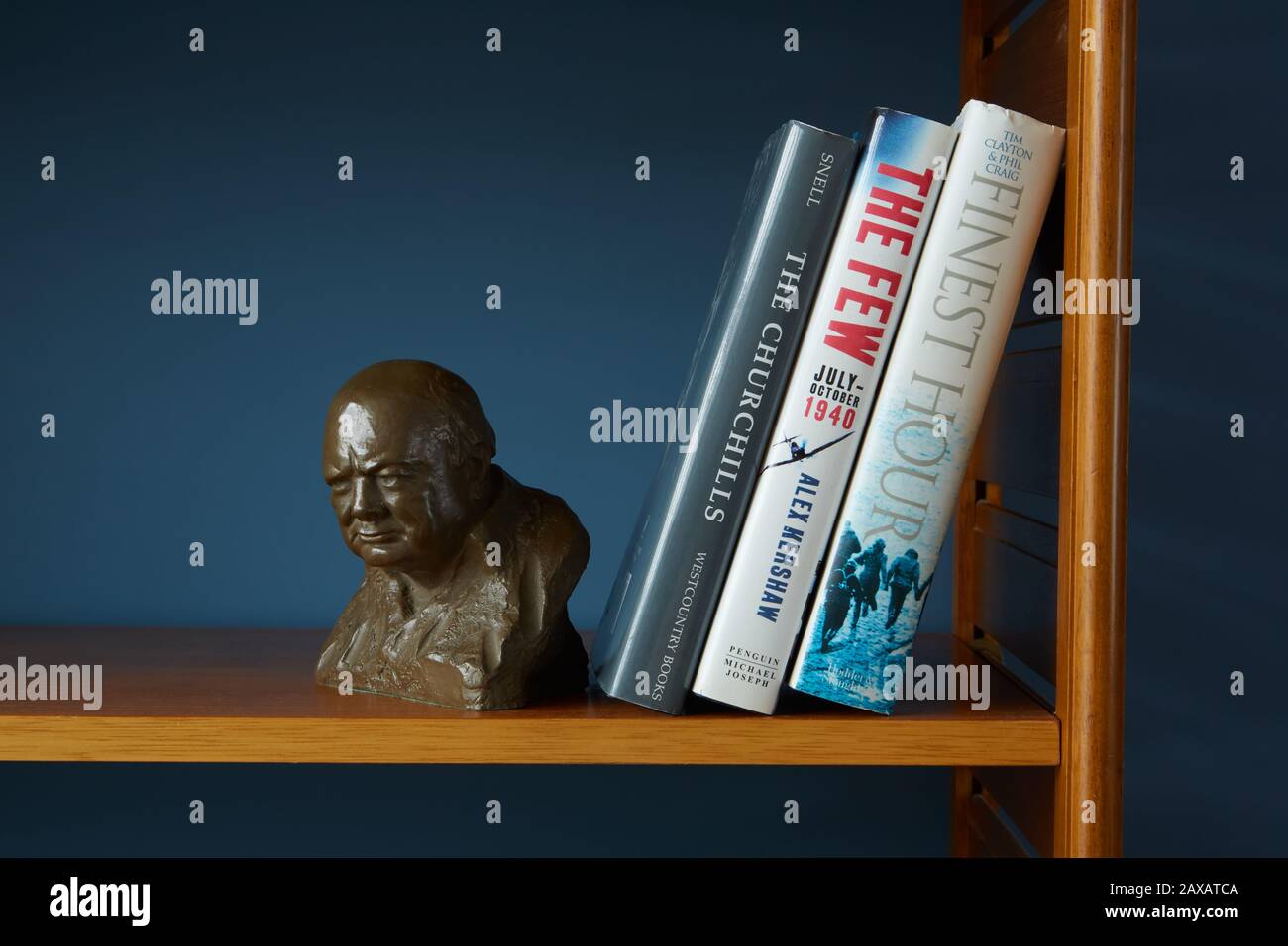 Un busto di Sir Winston Churchill messo su una mensola insieme con i libri circa la sua vita e La Seconda guerra mondiale. Su unità in teak con sfondo blu. Foto Stock