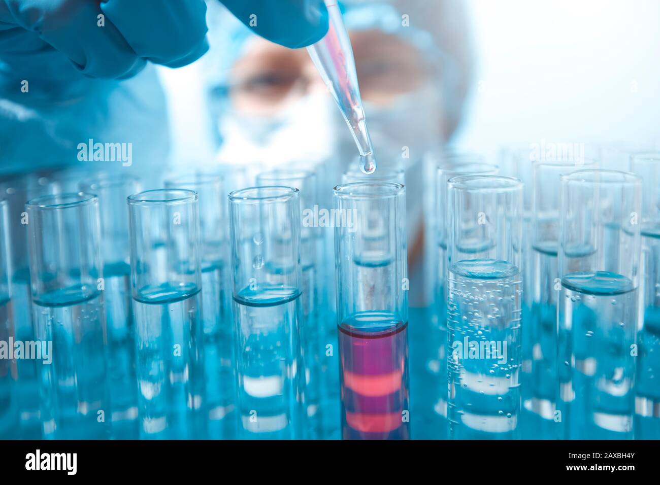 Pipetta da laboratorio in una provetta che gocciola liquido a mano del medico. Foto Stock