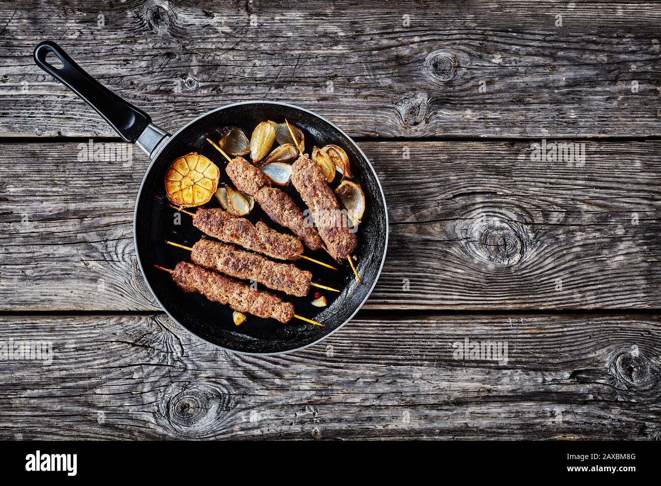 Piatto mediterraneo: Kofta kebab di carne macinata di agnello arrosto su spiedini con spezie mix: Sumac, allspezia, noce moscata servito su una padella con aglio e oni Foto Stock