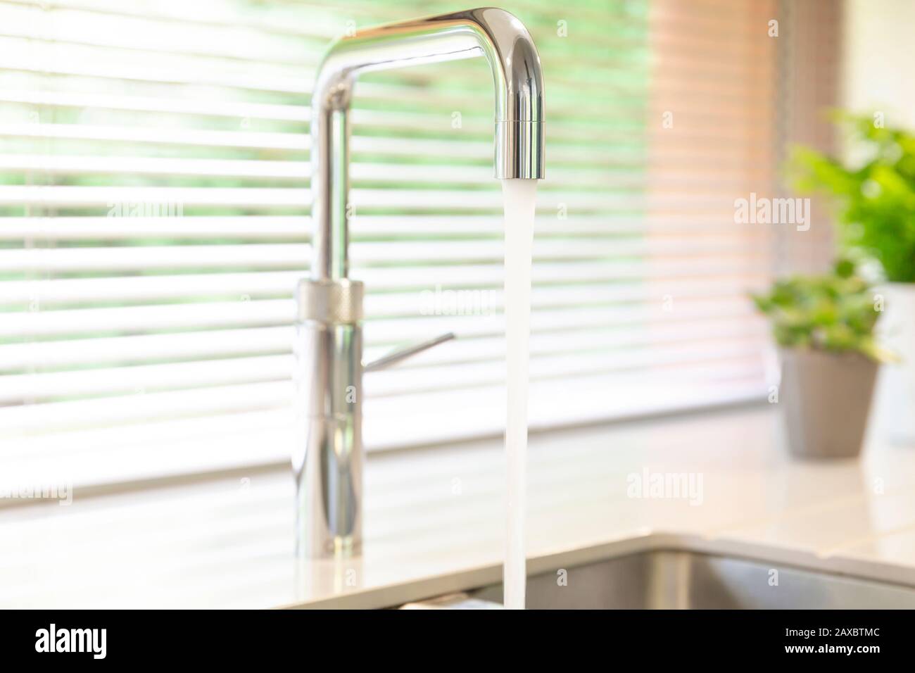 Chiudere l'acqua che scorre dal rubinetto della cucina in acciaio inossidabile Foto Stock