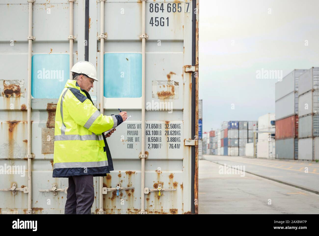 Lavoratori portuali che controllano i contenitori di carico presso il cantiere navale Foto Stock