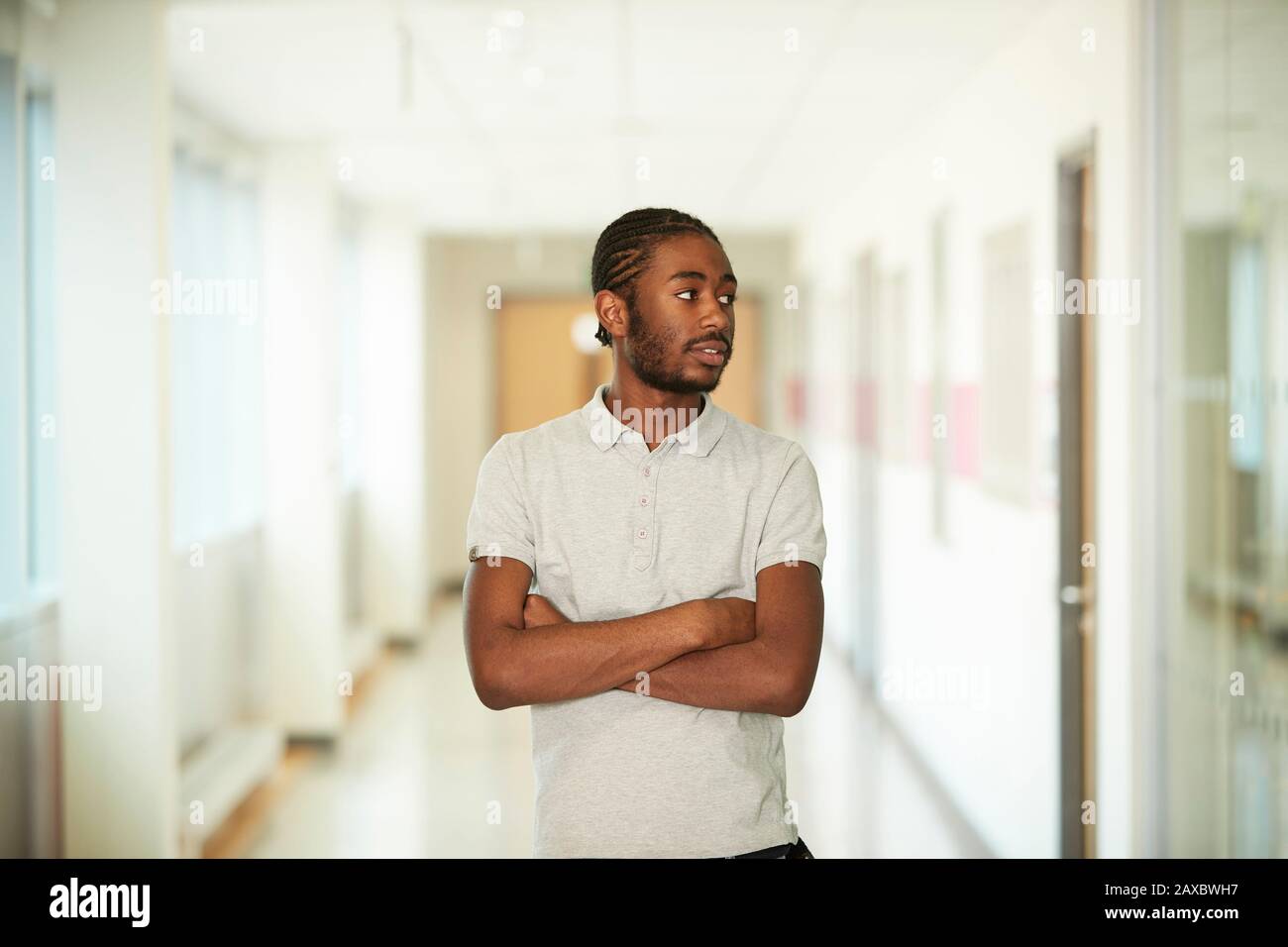 Ritratto giovane fiducioso con le braccia incrociate nel corridoio Foto Stock