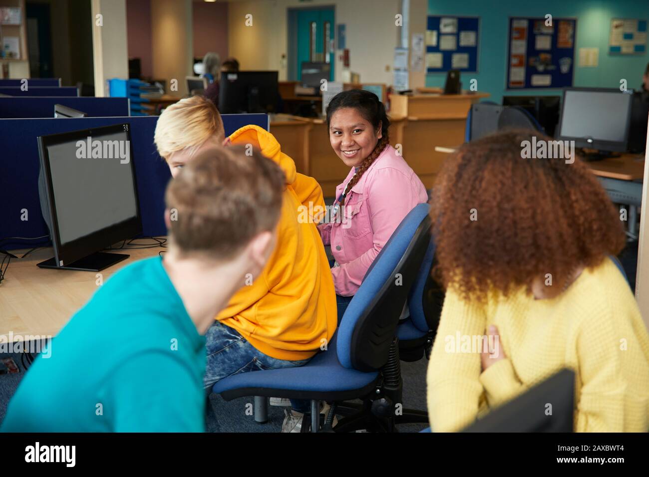 Studenti universitari felici che parlano e studiano in biblioteca Foto Stock