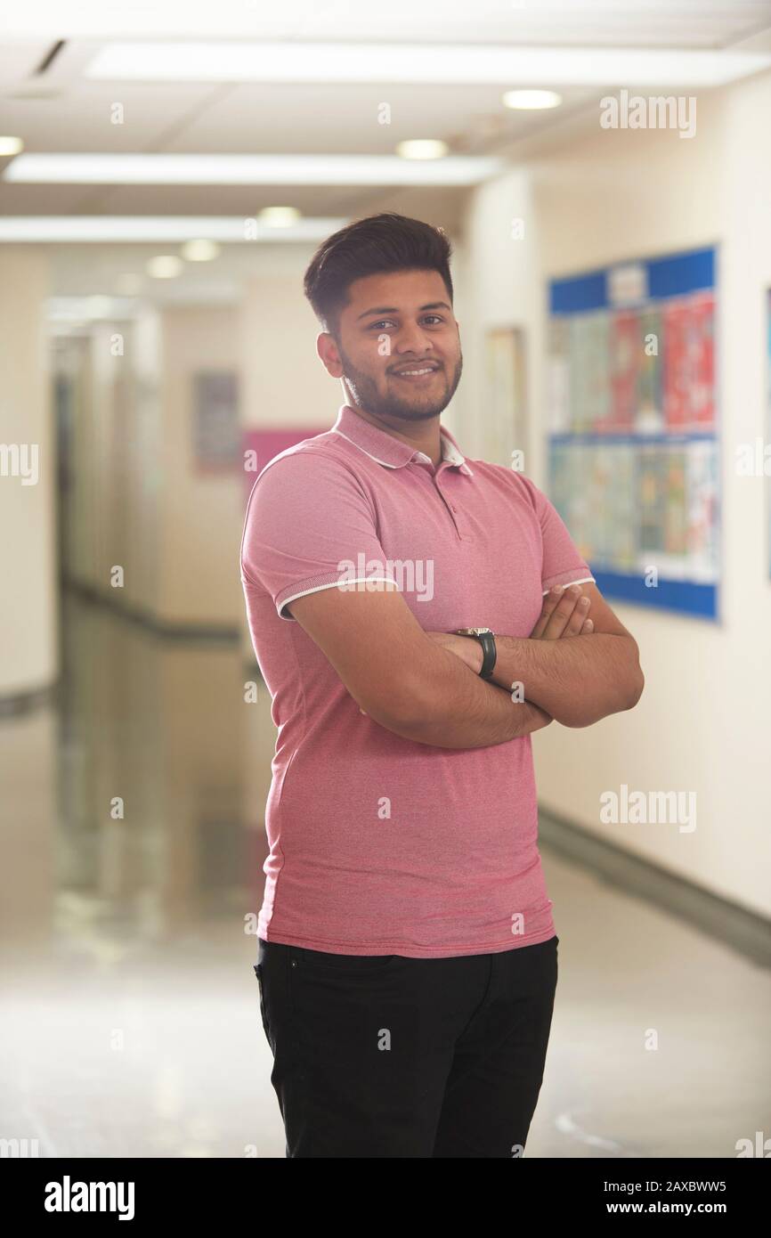 Ritratto fiducioso giovane studente di college maschile in corridoio Foto Stock