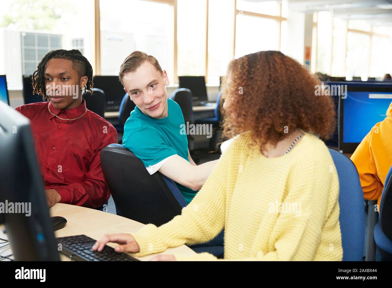 Studenti universitari che studiano insieme a computer in biblioteca Foto Stock