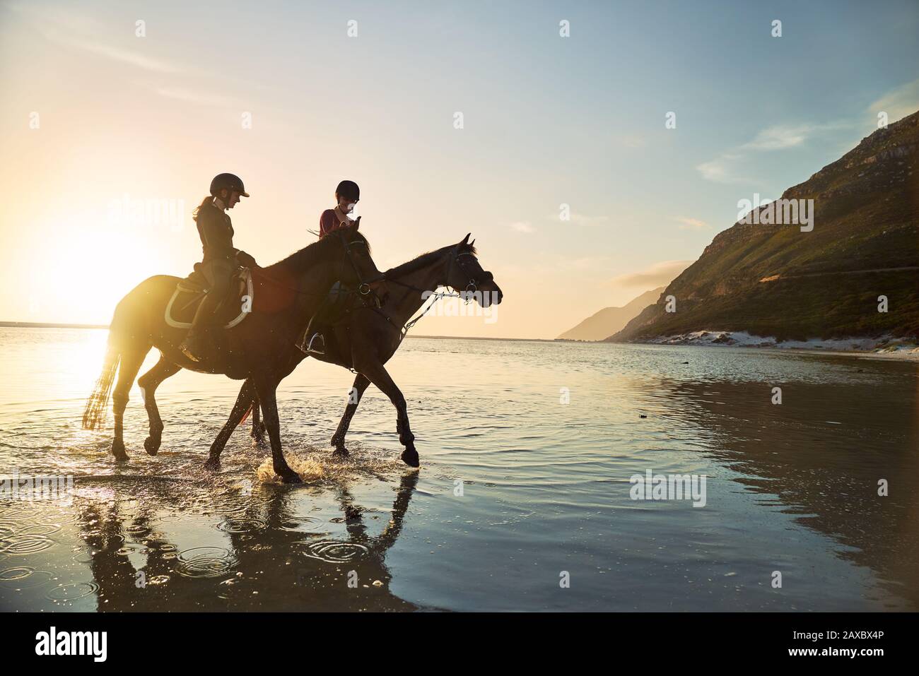Giovani donne equitazione al sole tramonto oceano surf Foto Stock