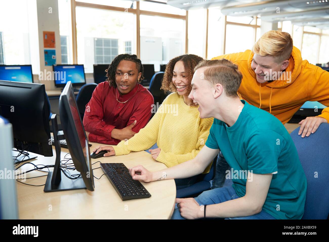 Studenti giovani felici che usano il computer insieme in biblioteca Foto Stock