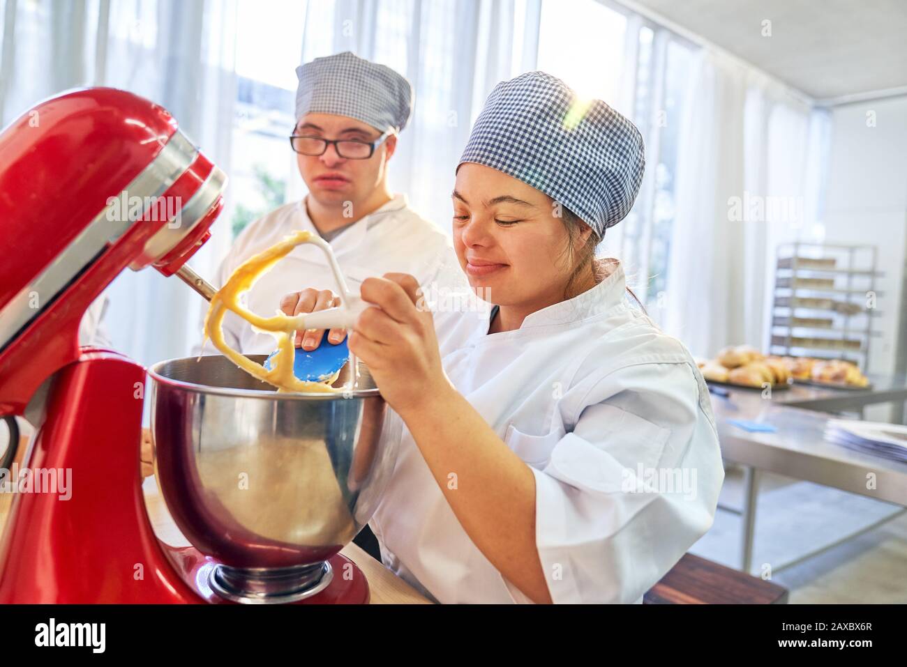 Giovani studenti con sindrome Di Down utilizzando stand mixer in classe di cottura Foto Stock