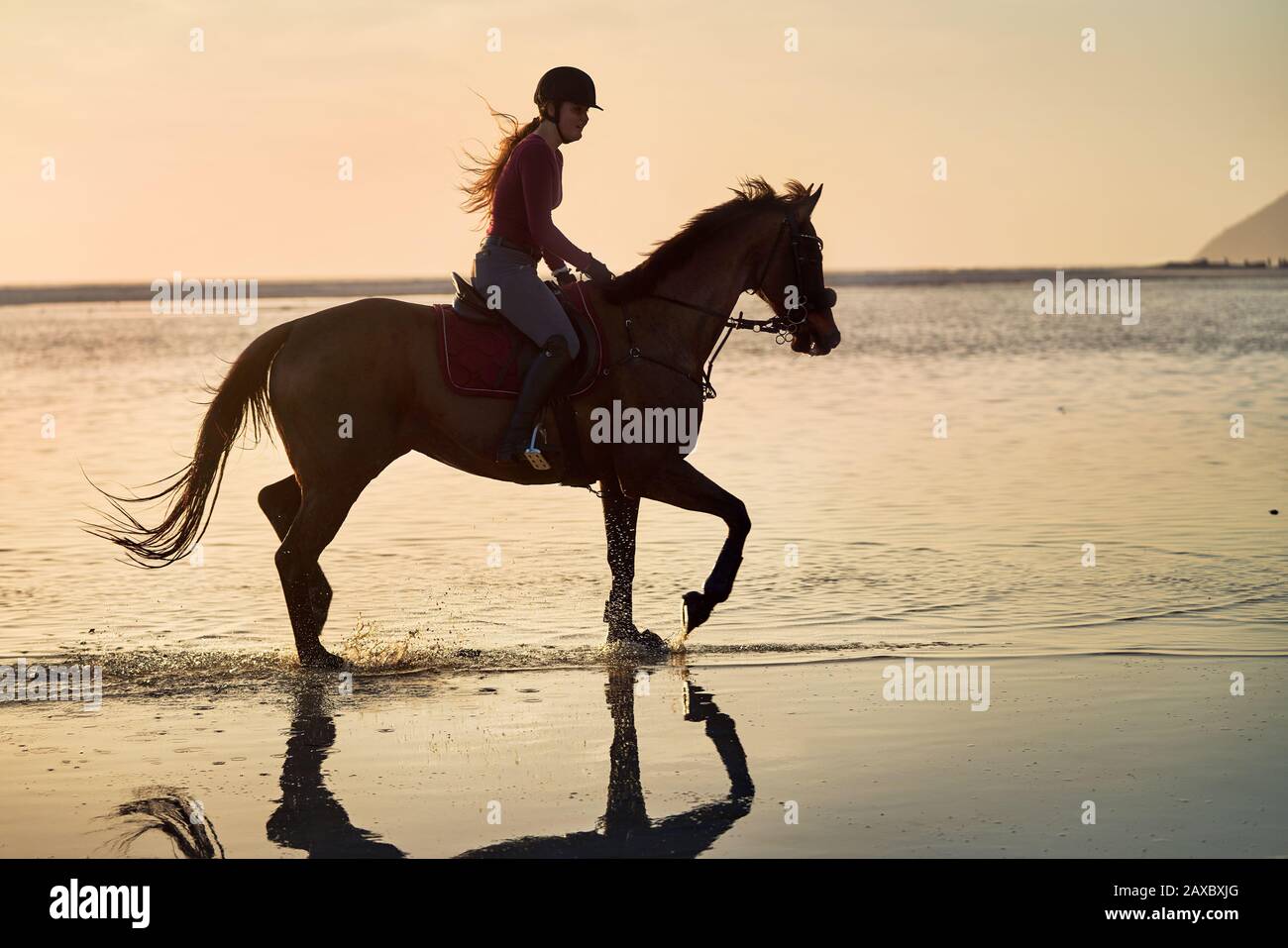 Giovane donna equitazione al tramonto oceano surf Foto Stock