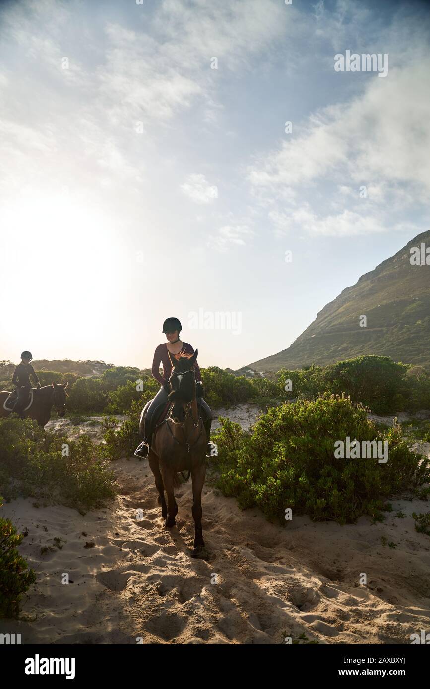 Giovane donna a cavallo sulla spiaggia soleggiata Foto Stock