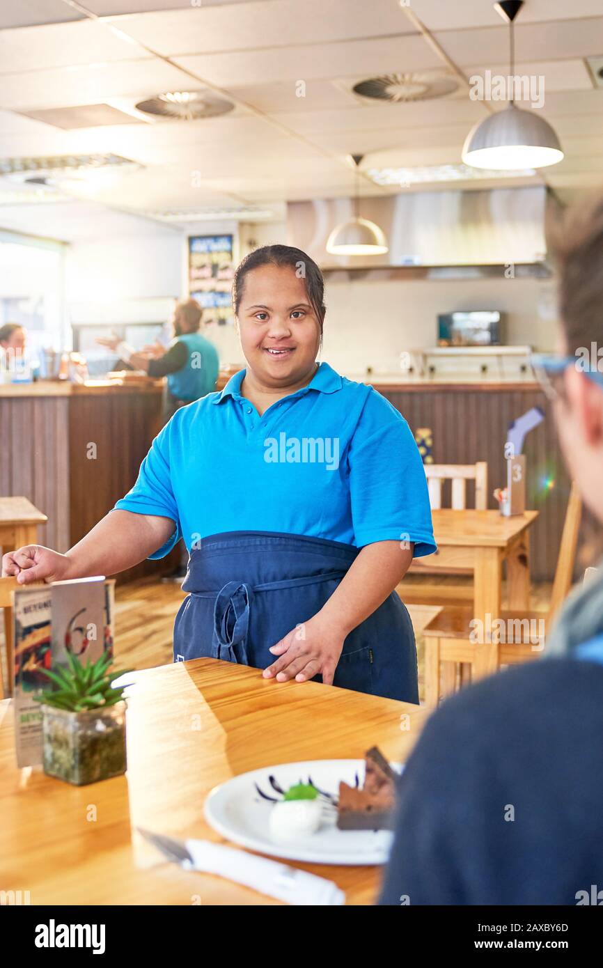 Ritratto sicuro giovane server femminile con sindrome Di Down in caffè Foto Stock