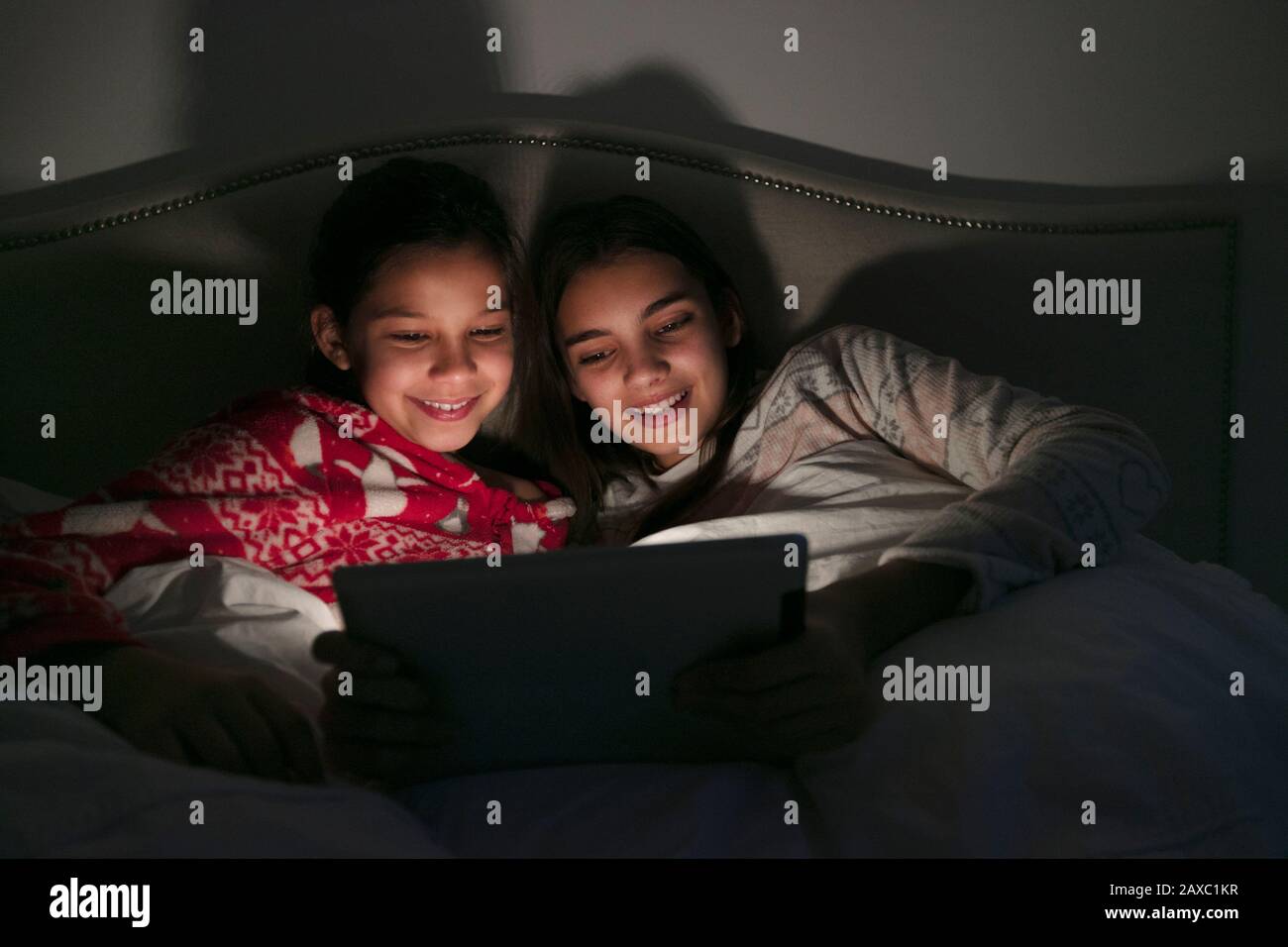 Ragazze che guardano film su tablet digitale in camera oscura Foto Stock