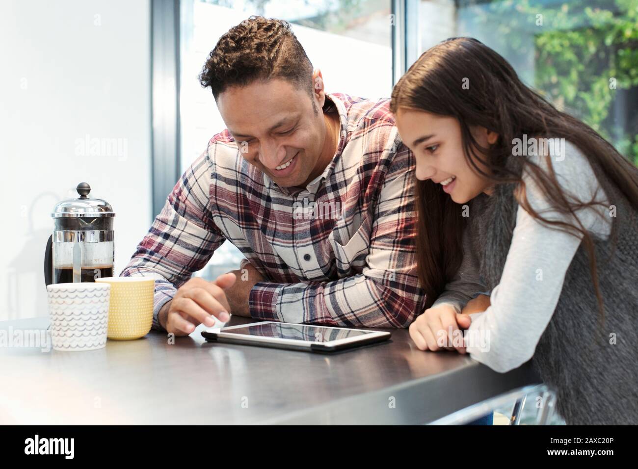 Sorridendo padre e figlia utilizzando un tablet digitale al bancone della cucina Foto Stock