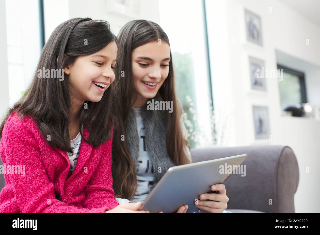 Buone sorelle che utilizzano un tablet digitale sul divano del soggiorno Foto Stock