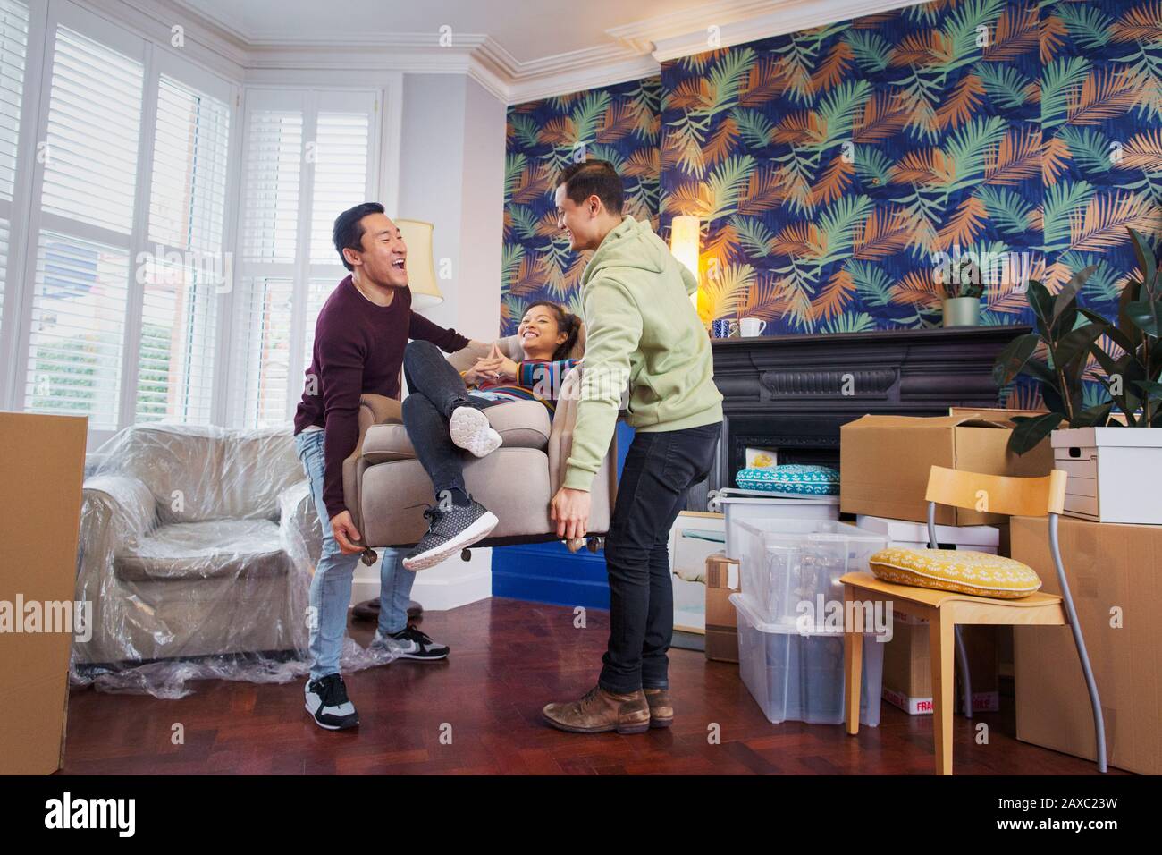 Amici giocosi che si spostano in una nuova casa Foto Stock