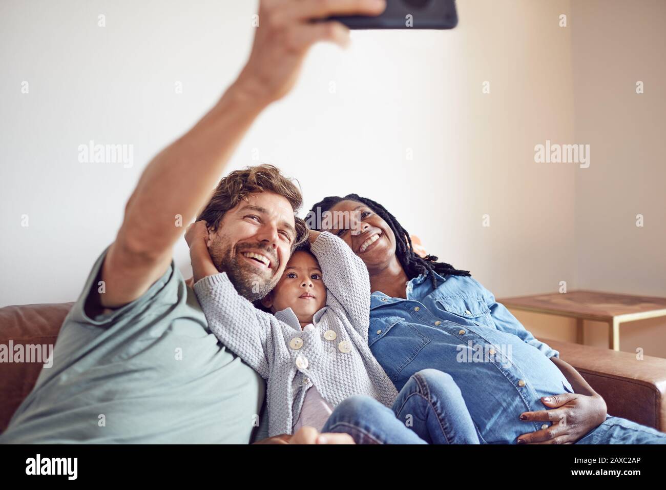 Giovane famiglia incinta felice che prende selfie Foto Stock