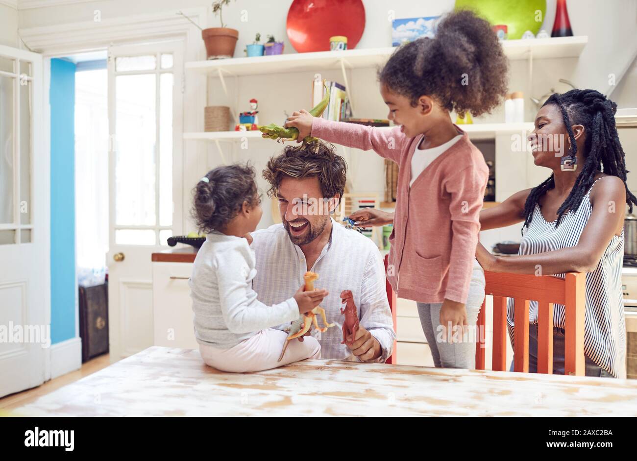 Giovane famiglia che gioca con i dinosauri giocattolo in cucina Foto Stock