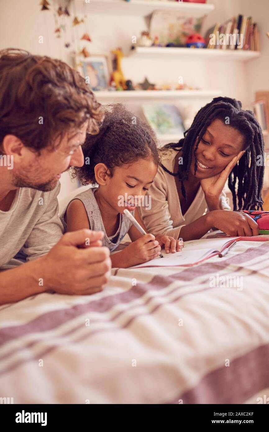 Giovane famiglia colorazione sul letto Foto Stock