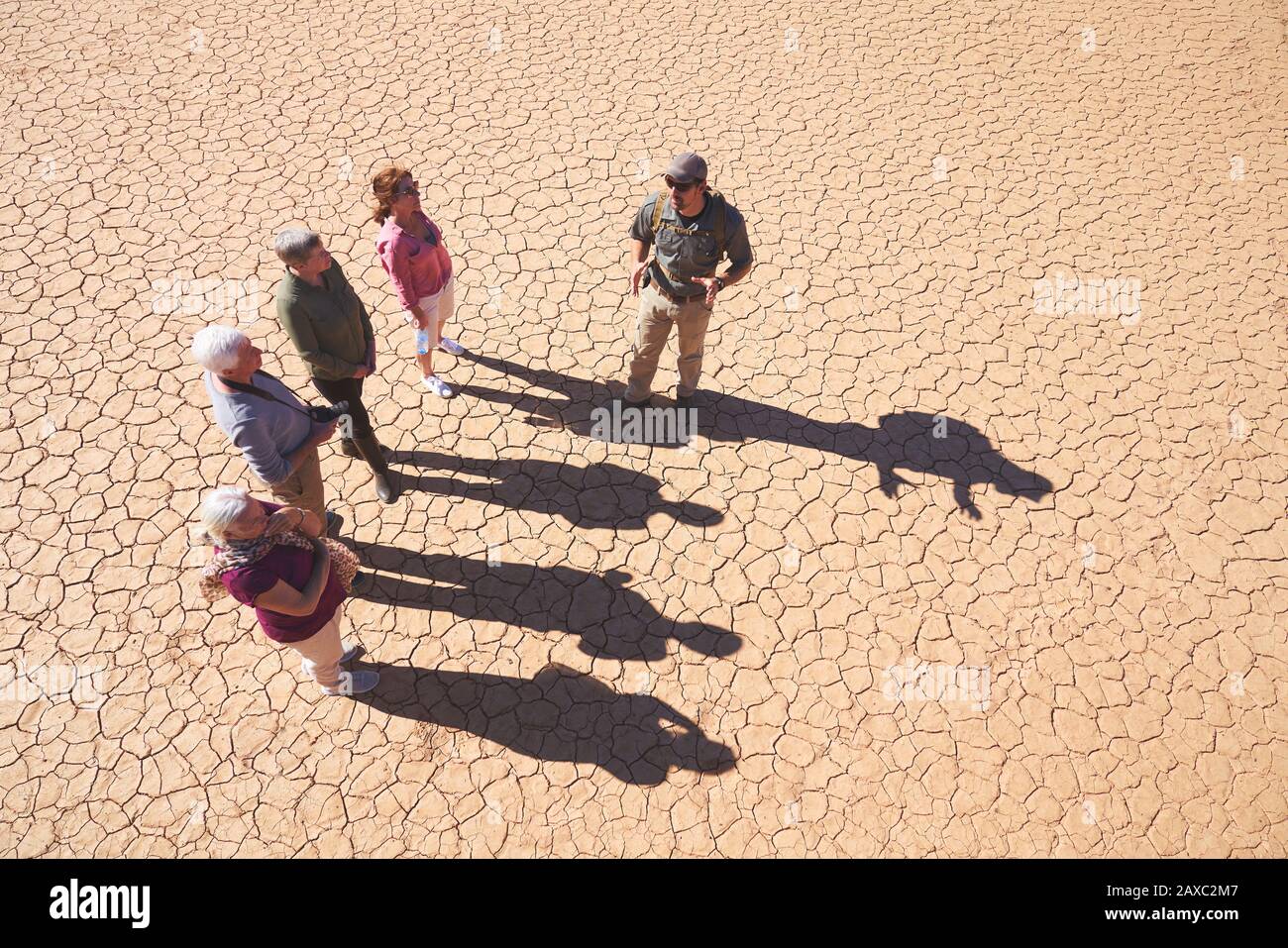 Guida turistica di Safari che parla con il gruppo su una terra piena di sole crepe Foto Stock