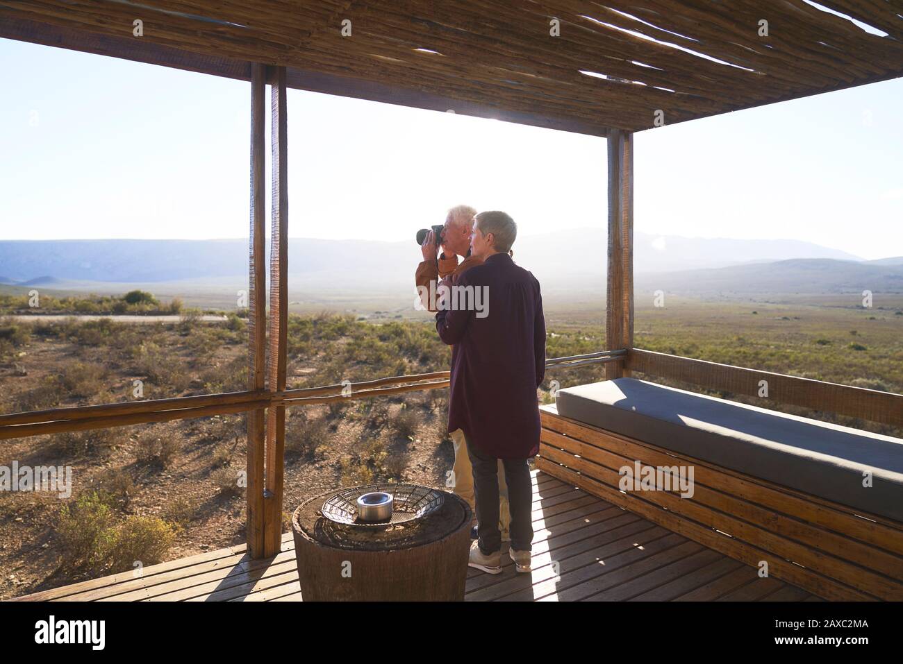 Coppia senior con macchina fotografica sul soleggiato balcone cabina safari Foto Stock